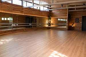 La salle Aquabob à Saint-Denis : parquet clair, murs lambrissés de bois, miroirs et barres le long du mur