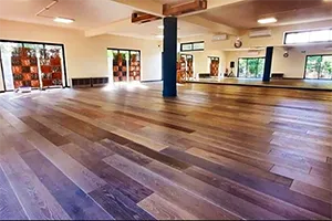 La salle La Petite Folie à La Saline : grand parquet, baies vitrées et pilier bleu au centre