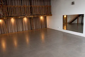 Le Studio Dojo Pierre Grondin à Sainte-Clotilde : sol carrelé, grand miroir mural et mezzanine en bois