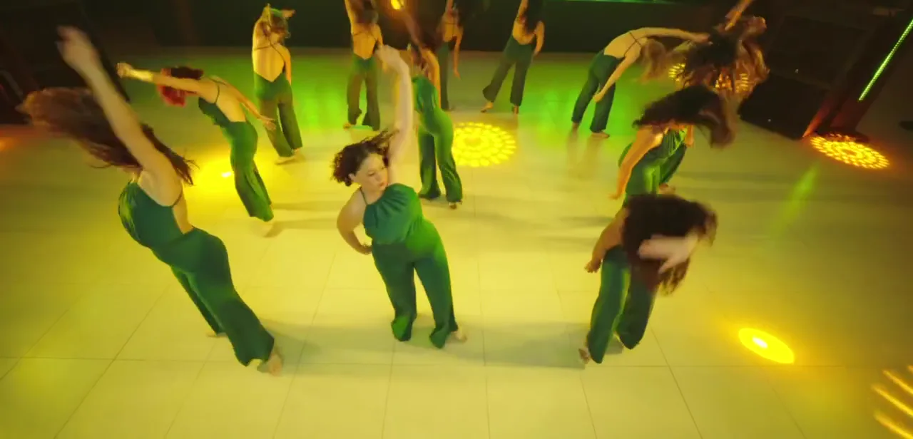 Une chorégraphie de Lady Style vue d’en haut : un groupe de danseuses en combinaison verte sur une piste éclairée
